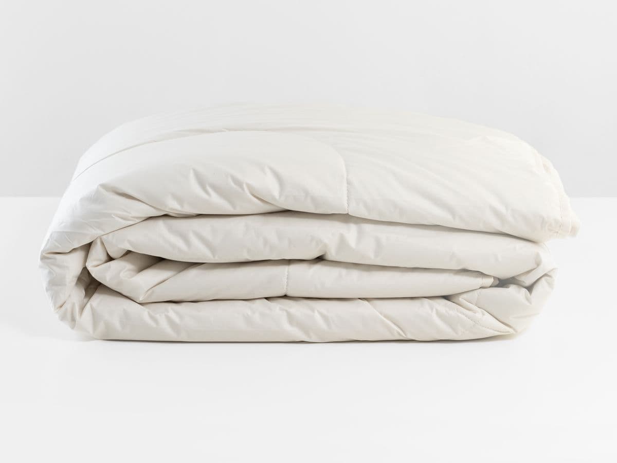 Alpaca duvet folded, showing the undyed organic cotton shell and the hand-closed edge